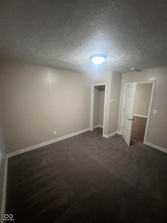 unfurnished bedroom featuring a textured ceiling and dark carpet