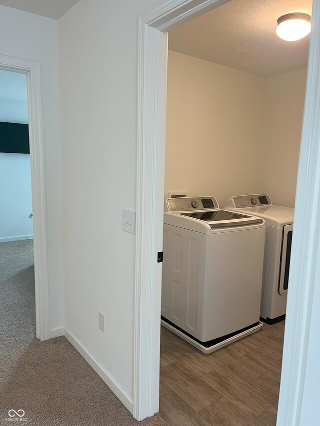 washroom featuring light carpet, a textured ceiling, and washer and dryer