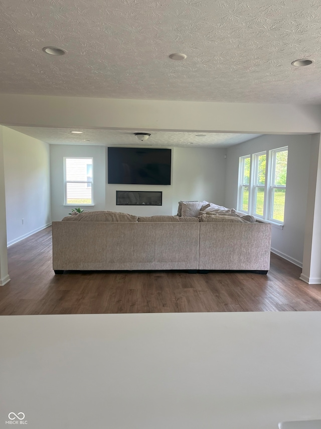 unfurnished living room with a textured ceiling and dark hardwood / wood-style floors