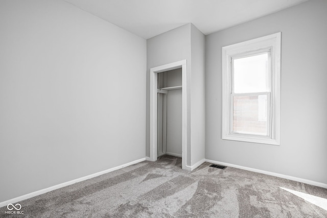 unfurnished bedroom with a closet and light colored carpet