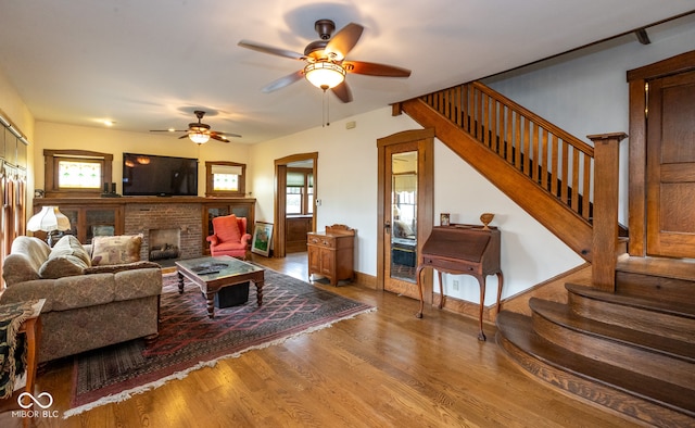 living room with a brick fireplace, hardwood / wood-style flooring, and ceiling fan