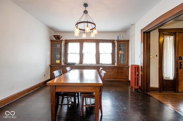 dining space featuring baseboards, wood finished floors, an inviting chandelier, and radiator