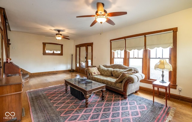 living room with wood finished floors, baseboards, ceiling fan, and french doors