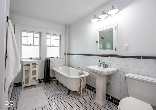 bathroom featuring tile walls, sink, toilet, and a washtub