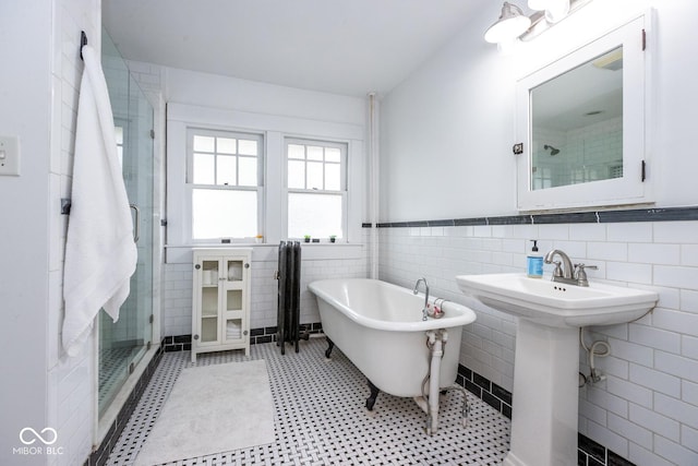 full bathroom with a soaking tub, a sink, tile walls, wainscoting, and a shower stall