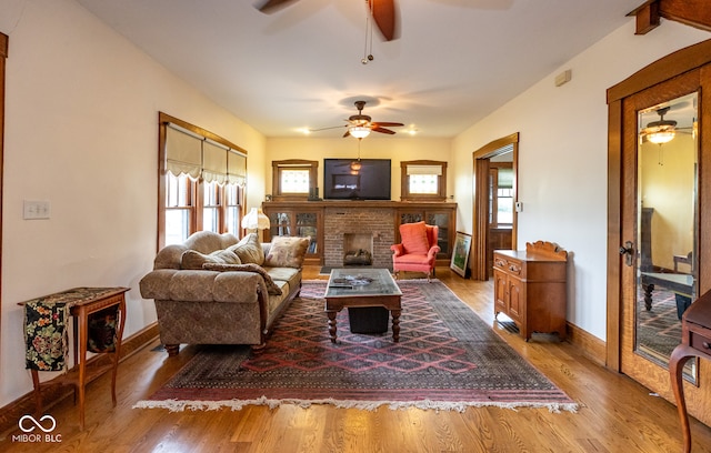 living room featuring a brick fireplace, hardwood / wood-style flooring, and ceiling fan