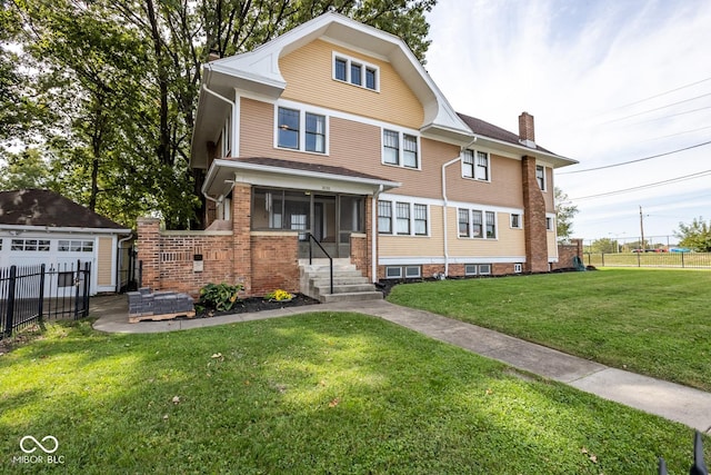 american foursquare style home featuring a chimney, fence, a front lawn, an outdoor structure, and a detached garage