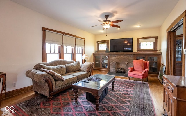 living room featuring wood finished floors, a brick fireplace, and a ceiling fan