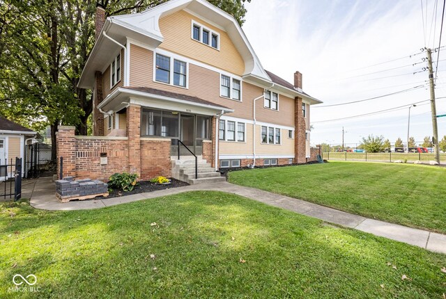traditional style home with a front yard, a chimney, and fence