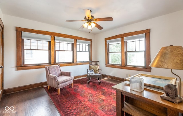 living area featuring wood finished floors, a ceiling fan, and baseboards