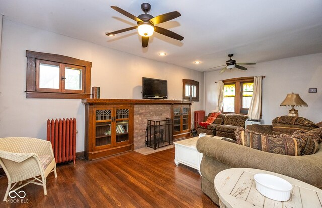 living room featuring dark wood finished floors, radiator, recessed lighting, a ceiling fan, and a fireplace