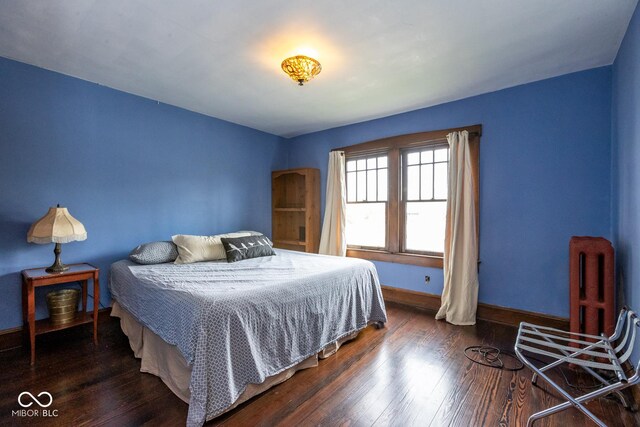 bedroom featuring baseboards, radiator heating unit, and wood finished floors
