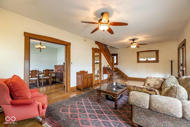 living room with wood finished floors, stairs, baseboards, and ceiling fan