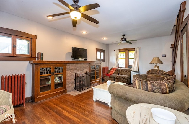 living room with radiator heating unit, wood finished floors, ceiling fan, a brick fireplace, and recessed lighting