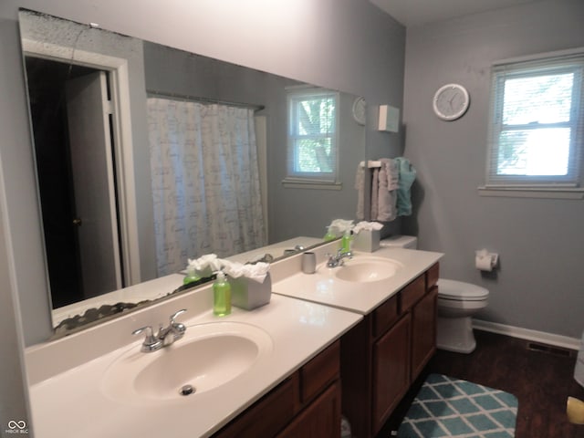 bathroom with wood-type flooring, vanity, walk in shower, and toilet