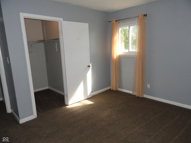 unfurnished bedroom featuring dark carpet and a closet