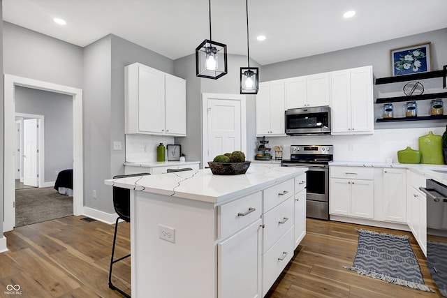 kitchen featuring dark wood-type flooring, appliances with stainless steel finishes, a center island, and white cabinetry