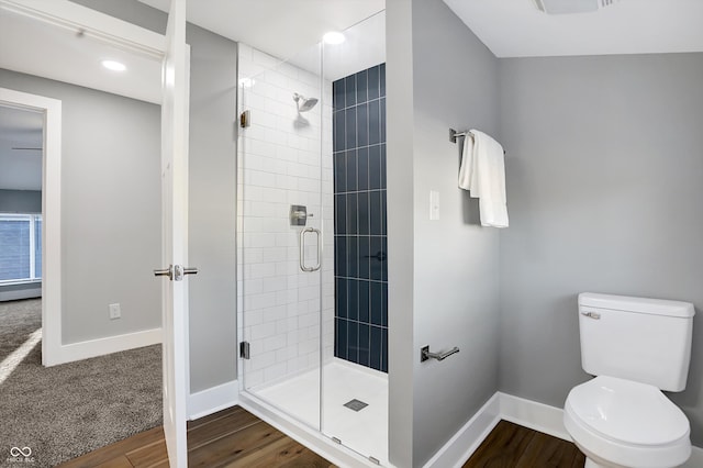 bathroom featuring a shower with door, hardwood / wood-style flooring, and toilet