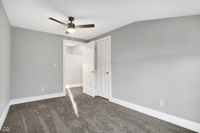 unfurnished bedroom with ceiling fan, lofted ceiling, and dark carpet