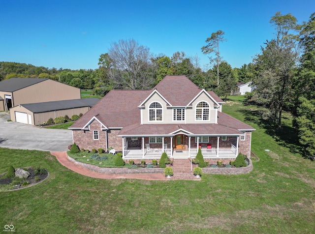 view of front of home featuring a garage, an outbuilding, a front lawn, and covered porch