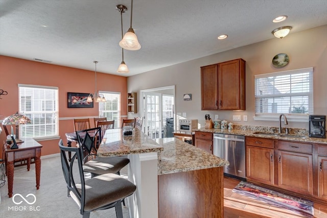 kitchen with dishwasher, light hardwood / wood-style floors, a center island, sink, and hanging light fixtures