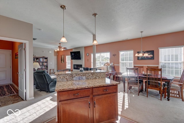 kitchen with ceiling fan with notable chandelier, a textured ceiling, light colored carpet, and decorative light fixtures