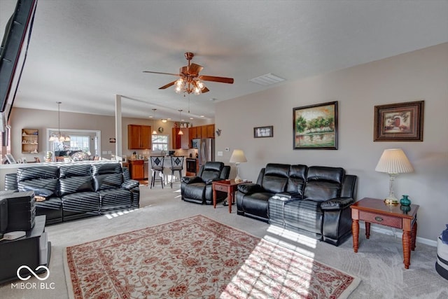 carpeted living room with ceiling fan with notable chandelier