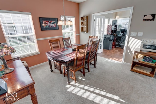 carpeted dining area with a healthy amount of sunlight and a notable chandelier