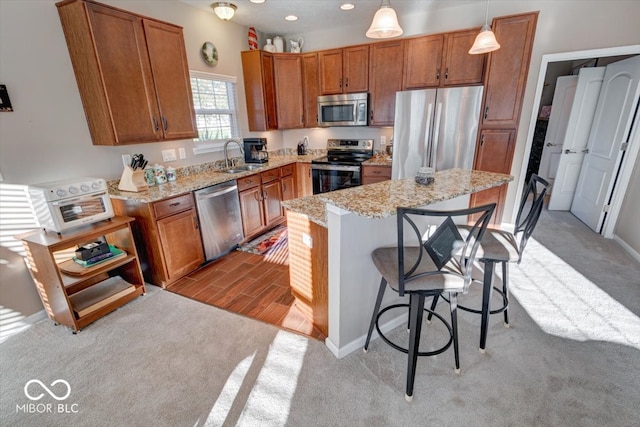 kitchen featuring pendant lighting, stainless steel appliances, light carpet, and a breakfast bar area