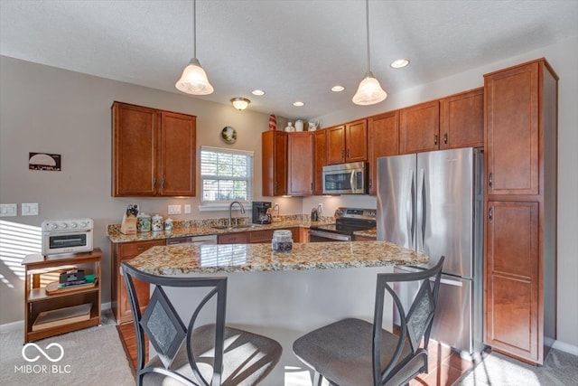 kitchen with sink, hanging light fixtures, a kitchen island, stainless steel appliances, and light stone countertops