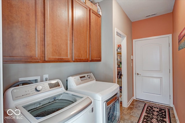 clothes washing area featuring washer and dryer and cabinets