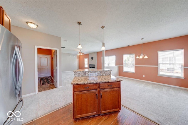 kitchen featuring pendant lighting, open floor plan, carpet flooring, and freestanding refrigerator