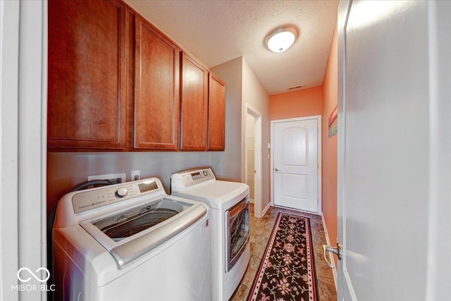 laundry room with baseboards, cabinet space, a textured ceiling, and washing machine and dryer