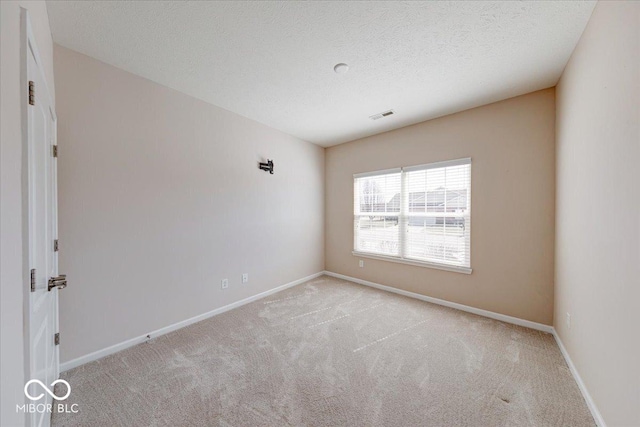 carpeted spare room featuring baseboards, visible vents, and a textured ceiling