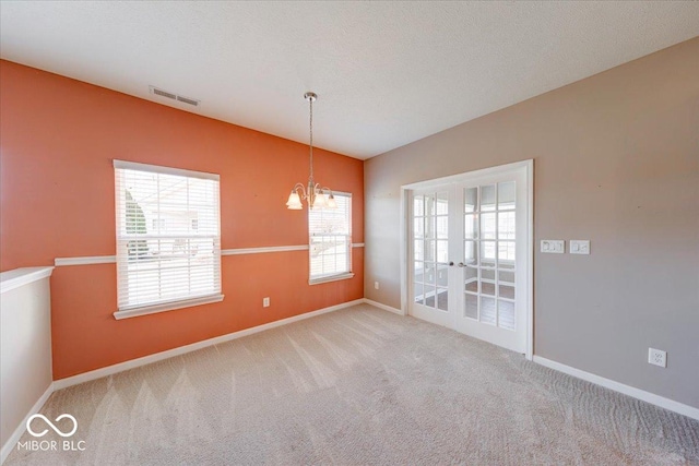 empty room with carpet, visible vents, baseboards, vaulted ceiling, and a notable chandelier