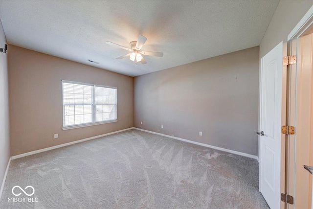 empty room with a textured ceiling, carpet, visible vents, and baseboards