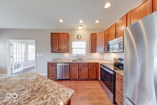 kitchen featuring recessed lighting, brown cabinets, appliances with stainless steel finishes, and a sink