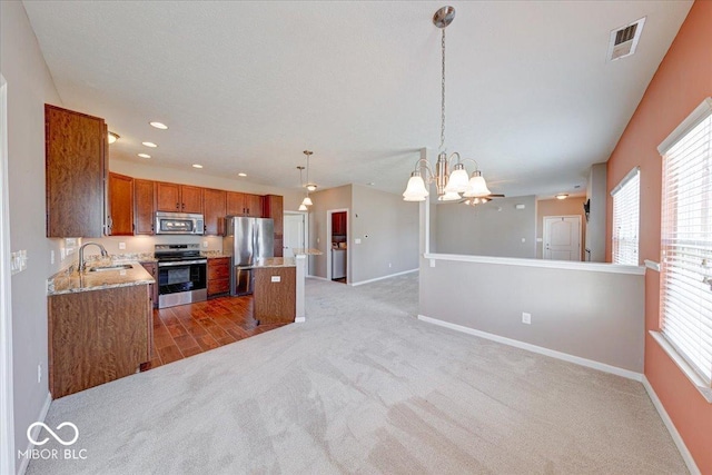 kitchen with visible vents, open floor plan, appliances with stainless steel finishes, brown cabinetry, and a sink