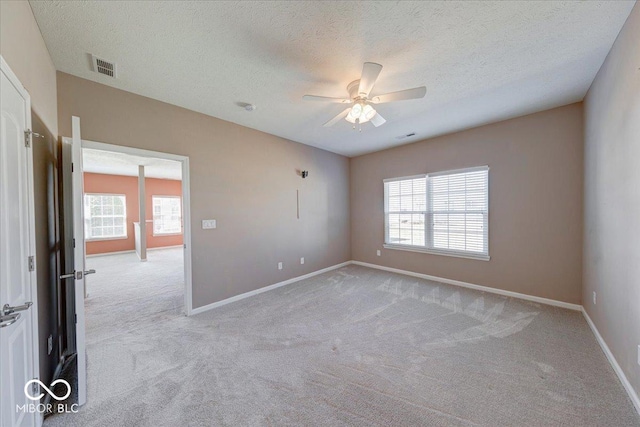 unfurnished room featuring ceiling fan, light colored carpet, visible vents, and baseboards