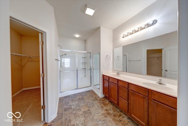 full bath featuring a sink, baseboards, a stall shower, and double vanity