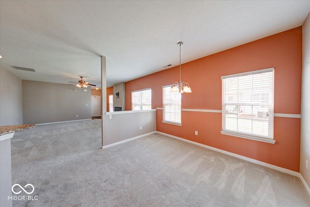 unfurnished room with ceiling fan with notable chandelier, carpet, visible vents, and a textured ceiling