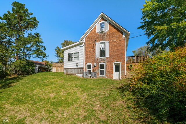 rear view of property featuring central AC and a lawn