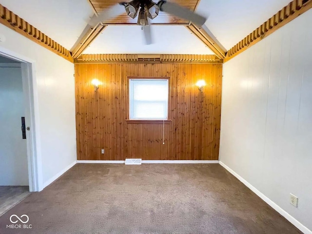 spare room with carpet, wooden walls, and ceiling fan