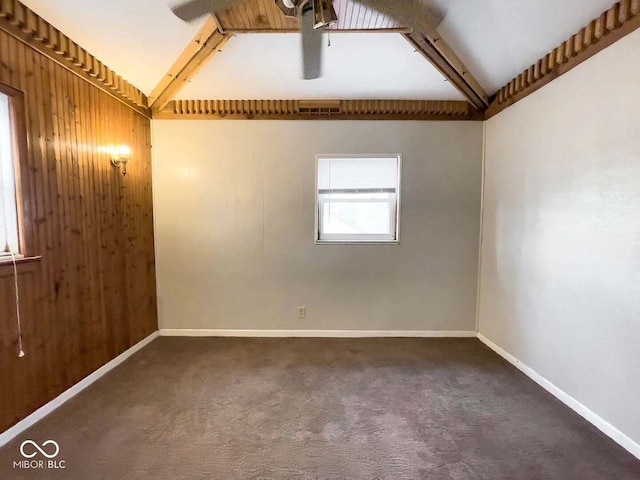 carpeted empty room with wood walls and beamed ceiling