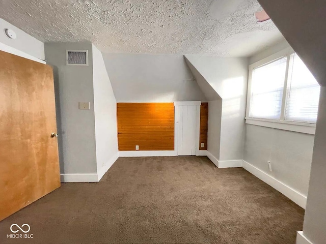 bonus room featuring dark carpet, vaulted ceiling, and a textured ceiling