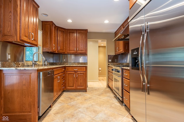 kitchen with appliances with stainless steel finishes, light tile patterned floors, stone counters, sink, and extractor fan