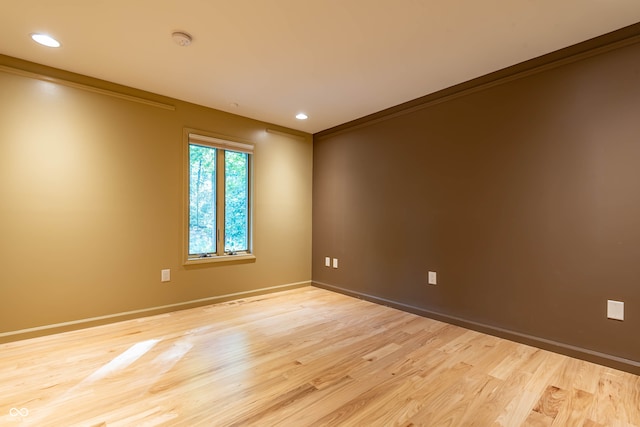 empty room with ornamental molding and light hardwood / wood-style floors