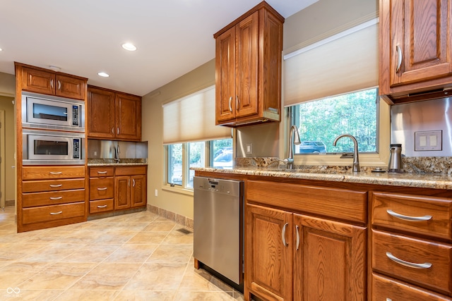 kitchen featuring light stone counters, light tile patterned flooring, appliances with stainless steel finishes, and sink