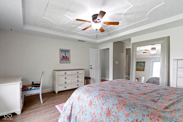 603 Ophelia Dr, Avon, IN 46123 - bedroom featuring a tray ceiling, wood finished floors, baseboards, a ceiling fan, and a textured ceiling
