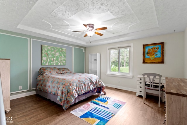 603 Ophelia Dr, Avon, IN 46123 - bedroom featuring a raised ceiling, wood finished floors, baseboards, a textured ceiling, and ceiling fan
